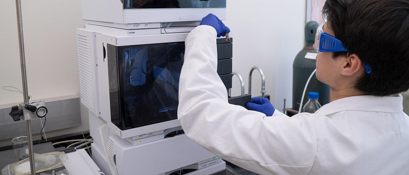 化学 student examining substance in a tube removed from lab equipment